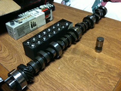 1972 Ford Ranchero - Camshaft and lifters are laid out on a wooden table next to a box of lifters.