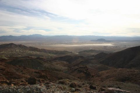 1991 Ford Bronco - Wide view of a desert landscape with mountains and a dry lake bed under a cloudy sky.