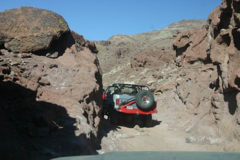 1991 Ford Bronco - A 1991 Ford Bronco navigates a narrow, rocky canyon trail under a clear blue sky.