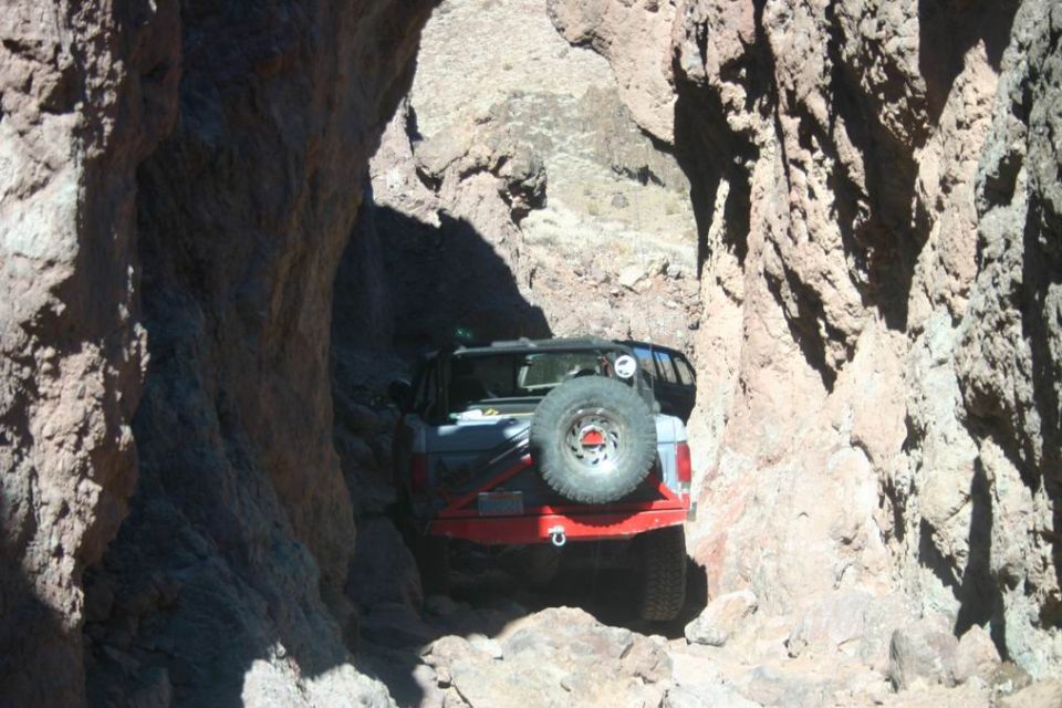 1991 Ford Bronco with spare tire on rear, driving through a narrow canyon