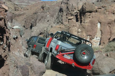 1991 Ford Bronco - Two off-road vehicles navigate a challenging rocky canyon trail, with one appearing to be stuck.