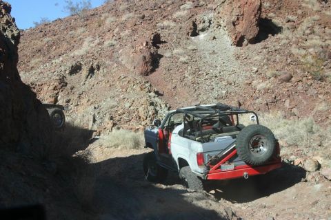 1991 Ford Bronco - A modified 1991 Ford Bronco navigates a rocky off-road trail, with another vehicle visible in the distance.