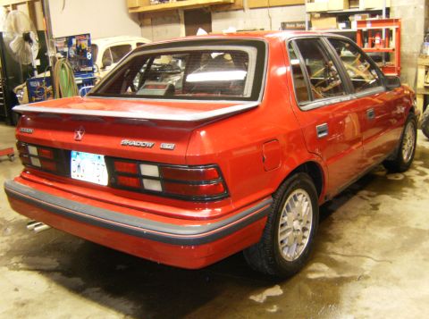2000 Ford E350 - Rear view of a red sedan with a spoiler and distinctive taillights, parked indoors.