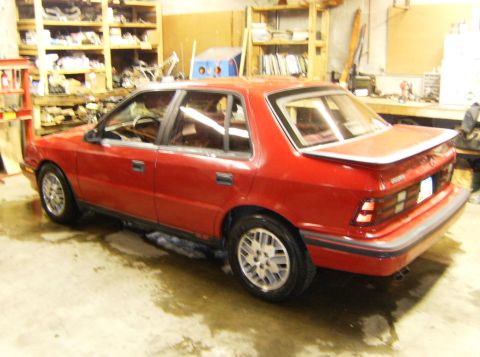 2000 Ford E350 - A red sedan with a spoiler is parked in a garage. The vehicle appears to be from the early 1990s.