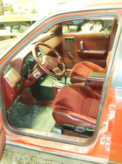 2000 Ford E350 - The interior of a car shows red velour seats and door panels, with the dashboard and steering wheel in view.