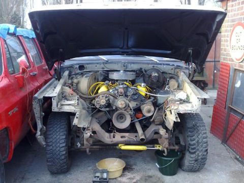 1978 Ford Bronco - Front view of a 1978 Ford Bronco's engine bay during a rebuild, with a red truck parked alongside.