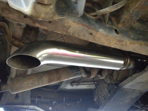 1989 Ford Bronco - Close-up view of a shiny chrome exhaust pipe attached to the undercarriage of a vehicle.