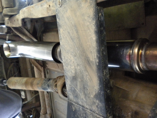 Underside view of shiny new metal tubing beside dusty chassis parts