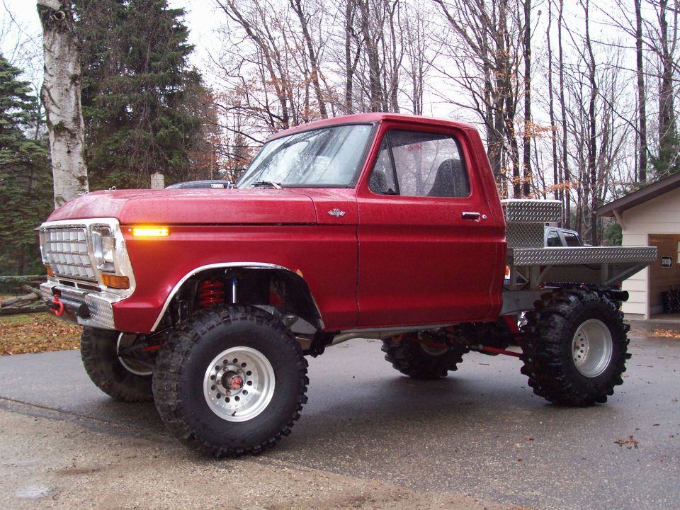 1978 Ford F-150 pickup truck, red, lifted with large off-road tires and a flatbed