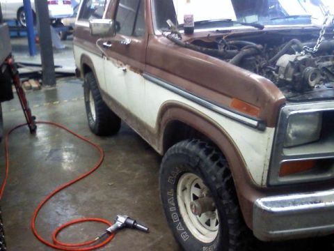 1985 Ford Bronco - Workshop scene with a 1980s Ford Bronco undergoing service, air tool nearby.