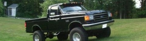 1979 Ford F-150 - This lifted black Ford pickup truck is viewed from a three-quarter front angle on a sunny day.