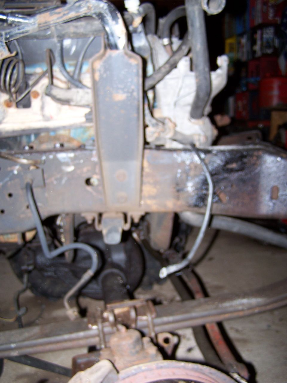 Close-up of a truck's rusty frame, suspension components, and part of the engine