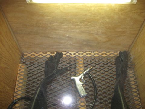 2004 Aston Martin Virage - Interior of a sandblasting cabinet, equipped with gloves and a tool for abrasive blasting.