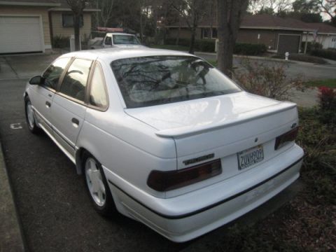 1993 Ford Taurus - White 1993 Ford Taurus sedan with a spoiler parked in a suburban driveway.