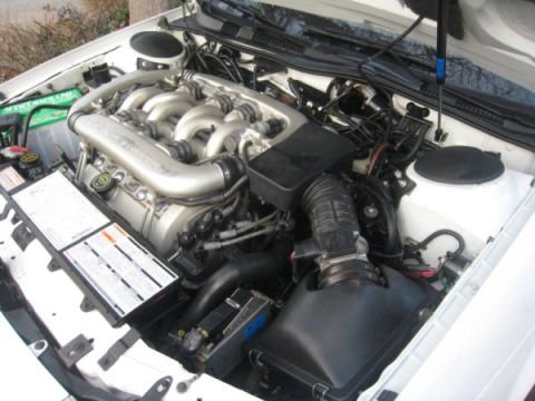 1993 Ford Taurus - The engine compartment of a white vehicle is shown with the hood open.
