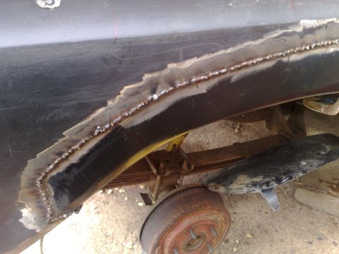 1978 Ford Bronco - Close-up of a vehicle's rear wheel well undergoing repair with fresh welding visible on the metal.