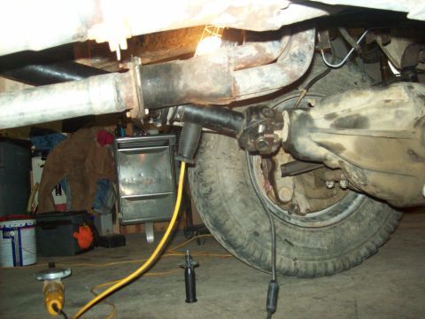 1971 Ford F-100 - Close-up view of the rear axle and drive shaft assembly of a vehicle, with tools and equipment on the floor.