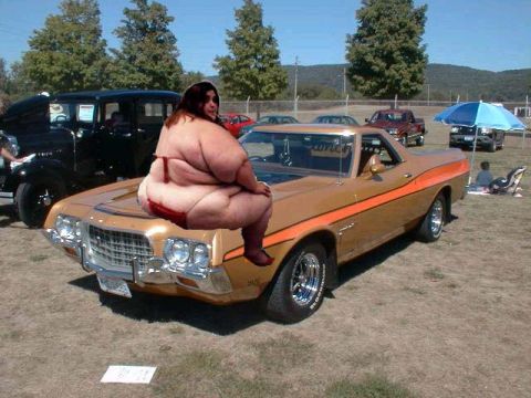 1971 Ford Ranchero - A woman sits on the hood of a gold 1972 Ford Ranchero with an orange stripe and chrome wheels.