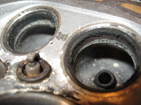 1991 Mitsubishi 3000GT - Close-up view of a cylinder head showing a spark plug and significant carbon deposits around the valve seats.