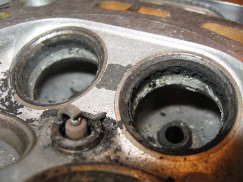 1991 Mitsubishi 3000GT - This is a close-up view of a used engine cylinder head, showing carbon buildup around the valve seats and a spark plug.