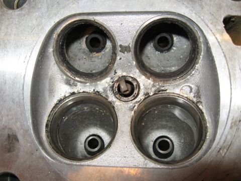 1991 Mitsubishi 3000GT - Close-up of a used engine cylinder head, revealing wear and deposits around the valve seats and spark plug well.