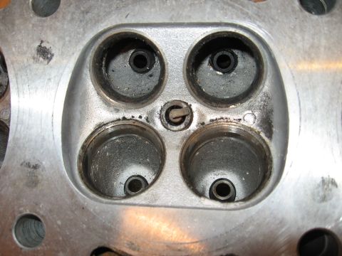 1991 Mitsubishi 3000GT - Close-up view of an engine cylinder head, showing the four valve ports and signs of carbon deposits.
