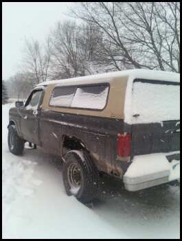 1996 Ford Bronco - A pickup truck with a camper shell is parked in a snowy outdoor setting.