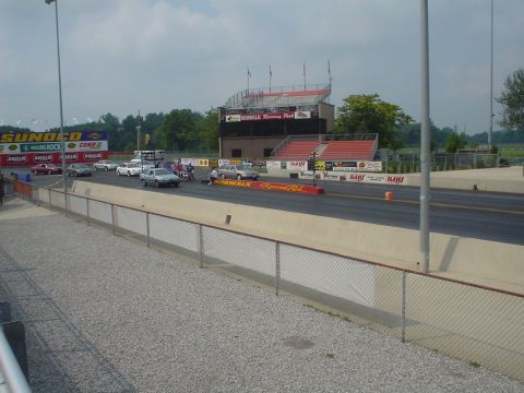 1999 Ford Taurus - Cars are staged at the starting line of a drag strip with grandstands visible.