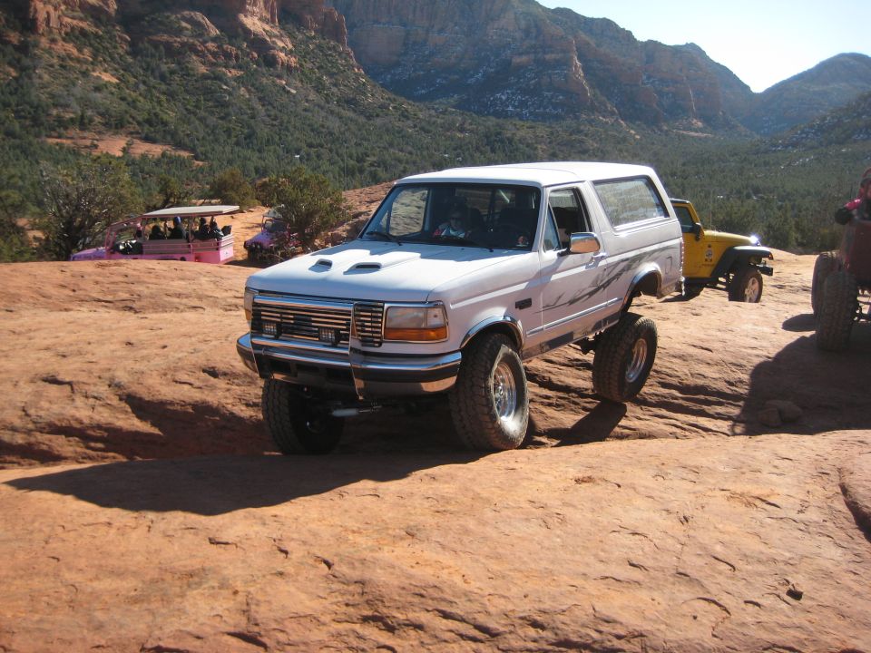 White 1996 Ford Bronco with lifted suspension on rocky terrain