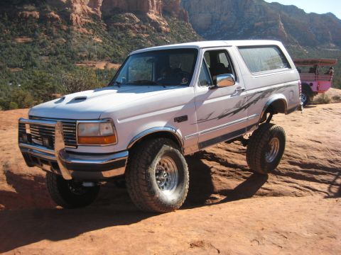 1996 Ford Bronco - A lifted 1996 Ford Bronco navigates a rocky trail, its off-road capabilities.