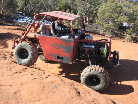 1996 Ford Bronco - A custom-built off-road buggy with flame decals navigates a rocky desert terrain.