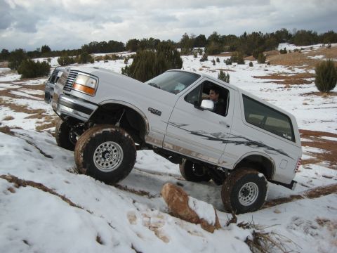 1996 Ford Bronco - 1996 Ford Bronco navigating a snowy trail with a second vehicle in the background.