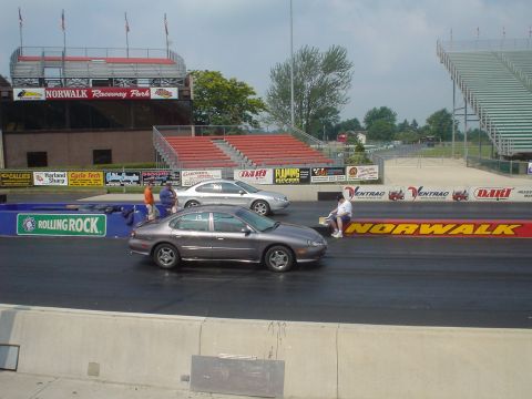 1999 Ford Taurus - Two sedans are lined up on the drag strip at Norwalk Raceway Park, ready for a race.