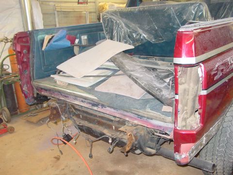 1984 Ford Bronco - Disassembled rear of a red pickup truck bed, showing interior storage and exposed components.