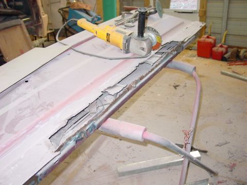 1984 Ford Bronco - A car door undergoing repair, showing significant rust damage and an angle grinder on its surface.