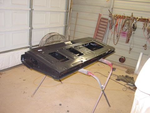 1984 Ford Bronco - A car door is propped up on a stand in a workshop, with tools and a garage door in the background.
