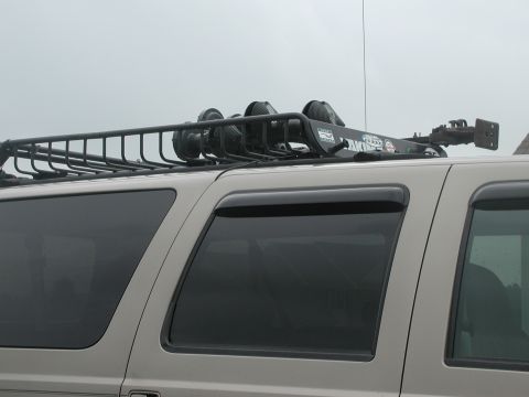 2000 Ford Excursion - A tan SUV, likely a 2000 Ford Excursion, is viewed from the side, showing its roof rack equipped with lights.