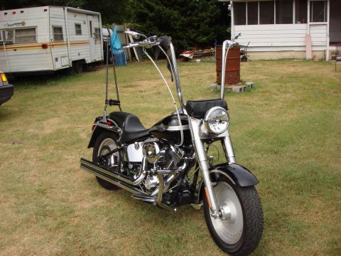 2003 Harley-Davidson Fat Boy - A black Harley-Davidson Fat Boy motorcycle is parked on a grassy lawn next to a trailer and a house.