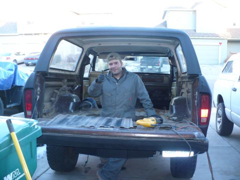 1979 Ford Bronco - A man stands in the cargo area of an SUV, giving a thumbs-up gesture while tools are visible on the tailgate.