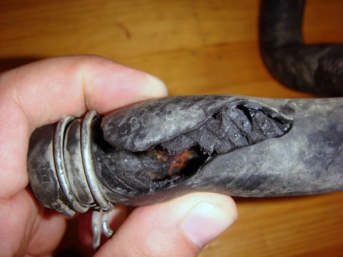 2000 Mitsubishi Montero - A damaged heater core hose is held by a hand, showing a large tear and internal degradation. Text '6803' is visible on the hose.