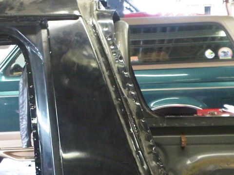 1996 Ford Bronco - Close-up of a vehicle's door frame with a green Ford Bronco visible in the background.