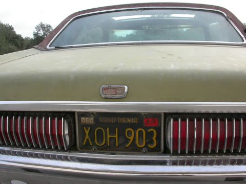 1968 Mercury Cougar - The rear of an olive green 1968 Mercury Cougar shows vertical taillights and a chrome bumper.