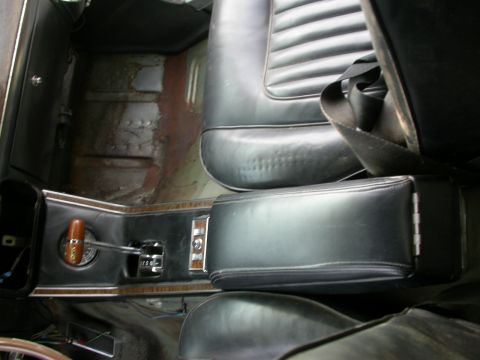 1968 Mercury Cougar - Interior shot of a car's center console and seats, a wooden gear shift knob and black upholstery.