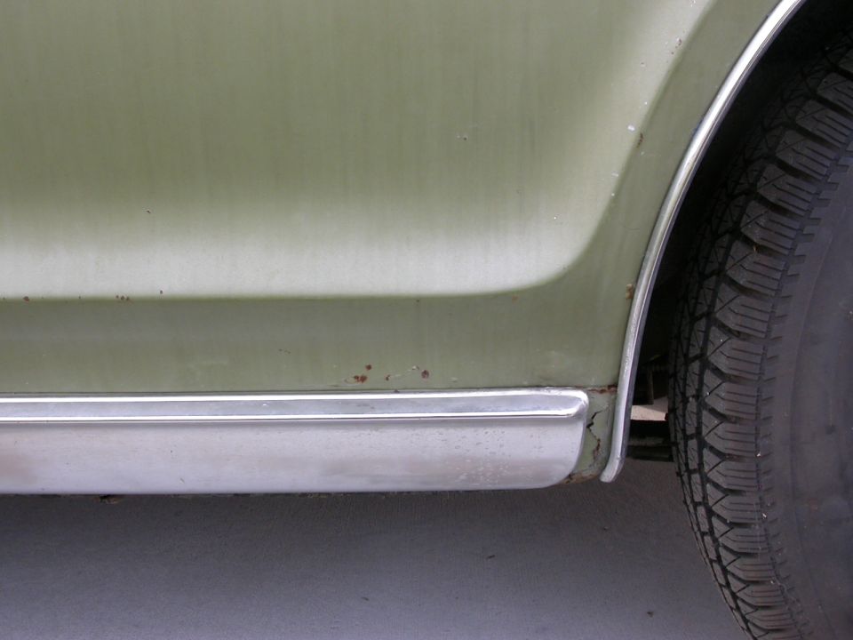 Green 1968 Mercury Cougar rear quarter panel and tire, showing rust spots and chrome trim