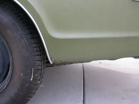 1968 Mercury Cougar - Close-up view of the rear quarter panel and tire of a 1968 Mercury Cougar, showing olive green paint and some rust.