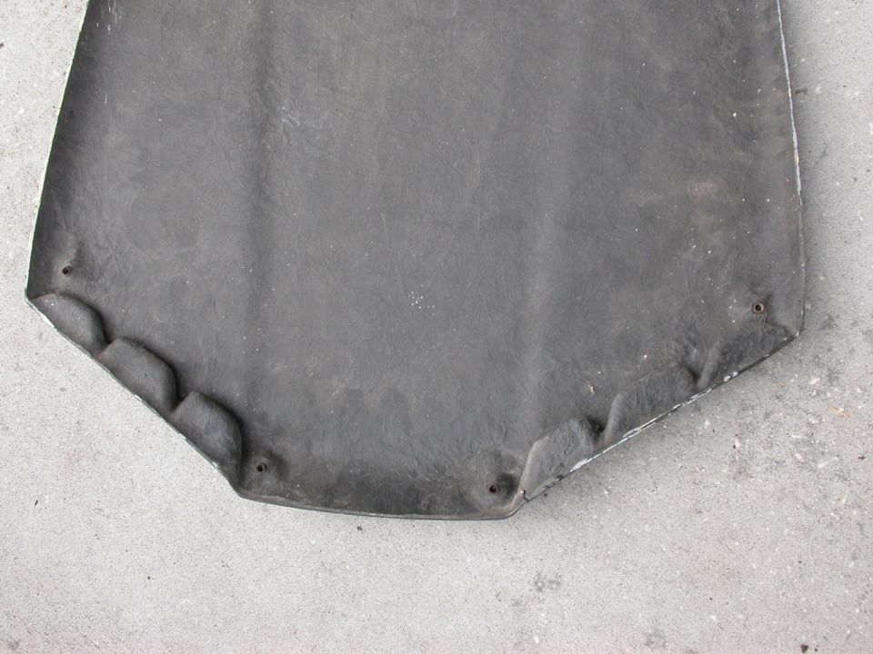 Underside of a dark gray car hood with visible mounting holes and textured surface