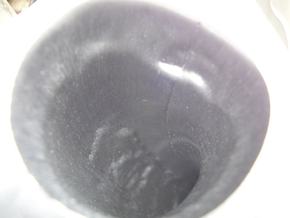 Close-up view inside a dark, cylindrical part with some white residue