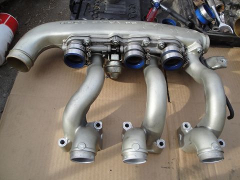 1993 Ford Taurus - Intake manifold with visible text and blue hose clamps, likely a car part.
