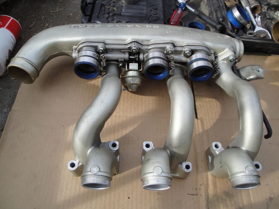 Silver intake manifold with blue-ringed connectors and vacuum actuator