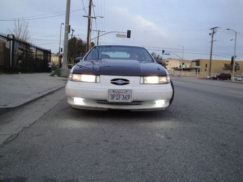 1993 Ford Taurus - This Ford Taurus, with its distinctive black hood, is parked on the side of a street.